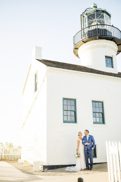 Newlywed couple standing for photos in front of Point Loma lighthouse.