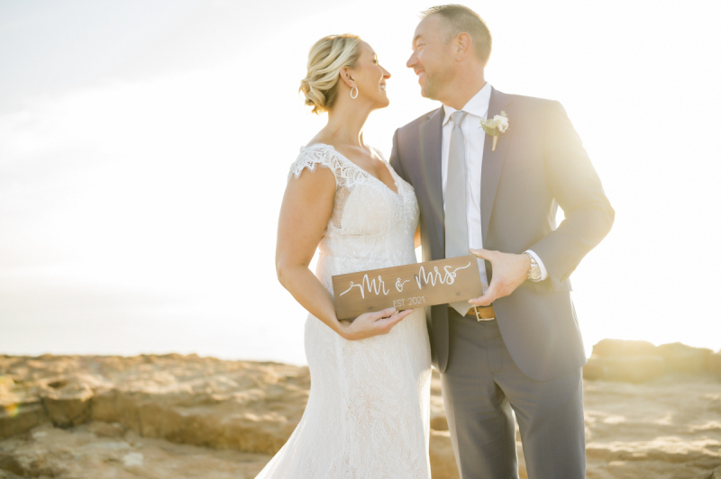 Bride and groom holding a Mr. And Mrs. wooden sign.