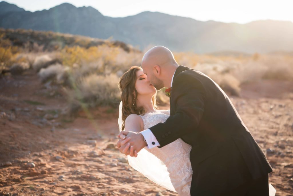 Groom kissing his bride after a desert wedding in Nevada.