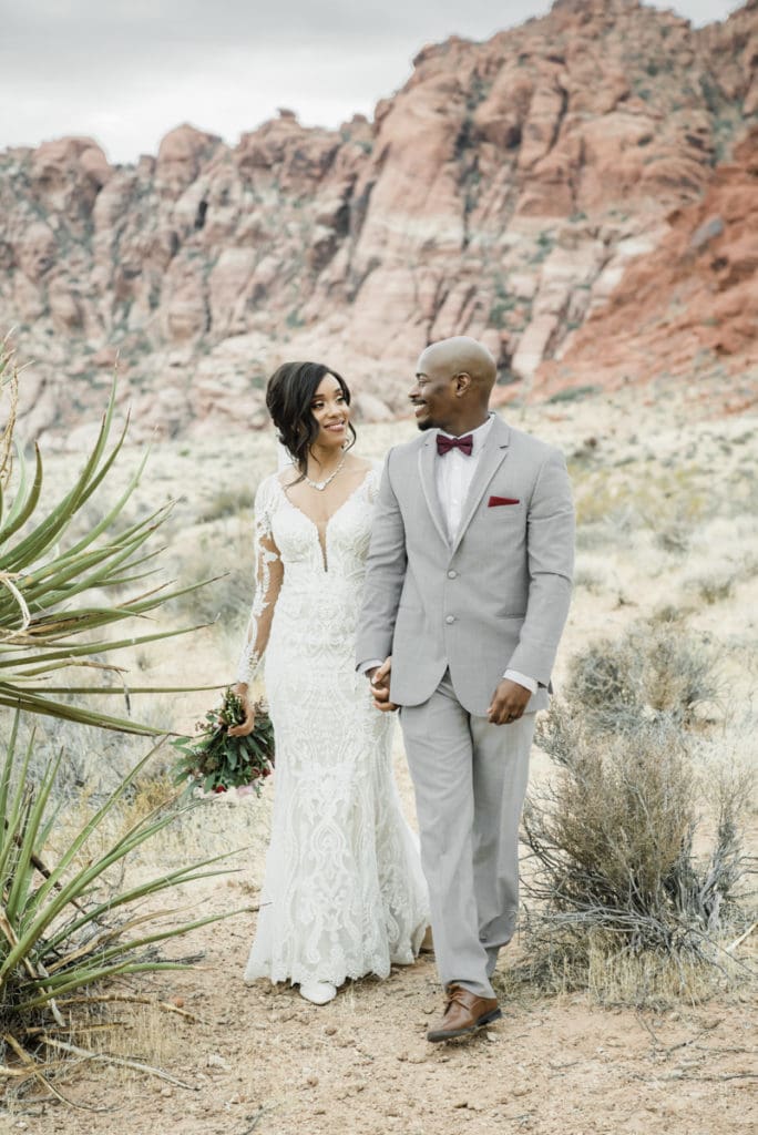 Shala & Michael walk hand in hand in the desert.