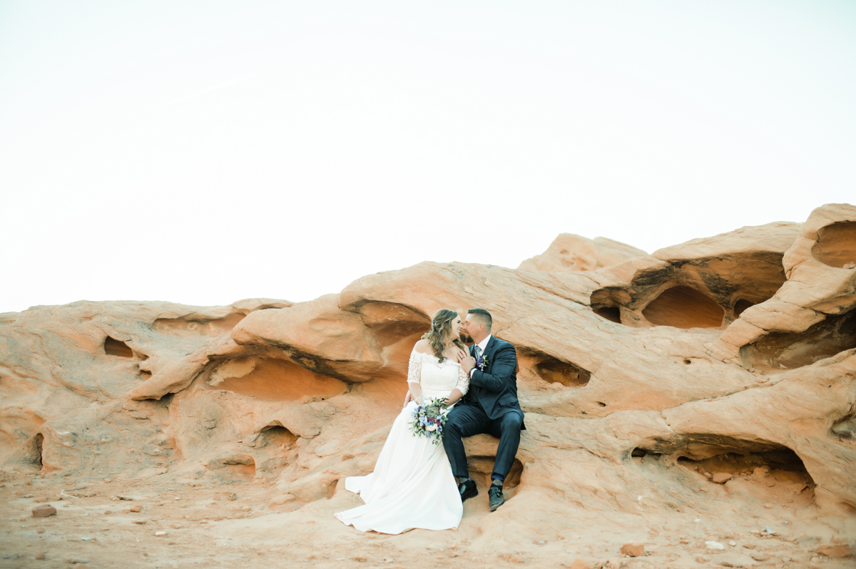 Bride and groom sitting on rock formation at Valley of Fire.